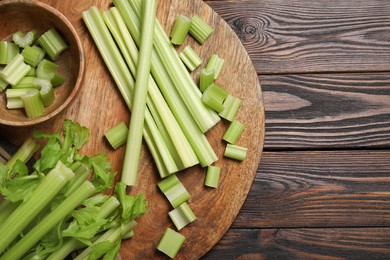 Photo of Board with fresh cut celery stalks on wooden table, top view. Space for text