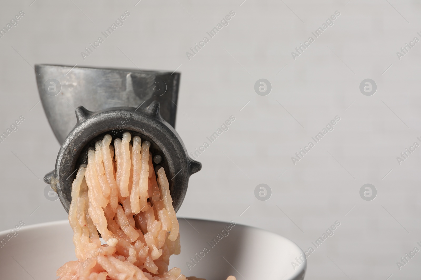 Photo of Metal meat grinder with chicken mince on light background, closeup. Space for text