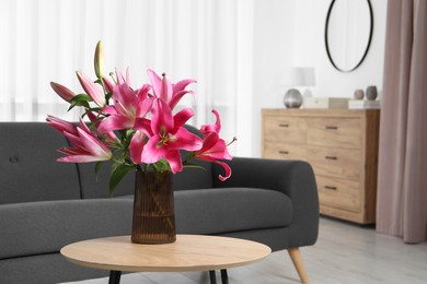 Photo of Beautiful pink lily flowers in vase on wooden table indoors, space for text