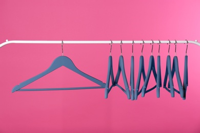 Metal rack with clothes hangers on color background