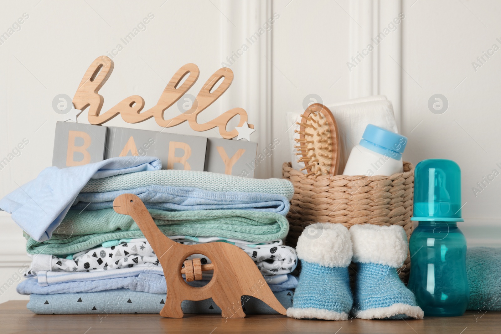 Photo of Baby clothes, toy and accessories on wooden table