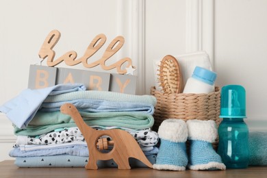 Photo of Baby clothes, toy and accessories on wooden table