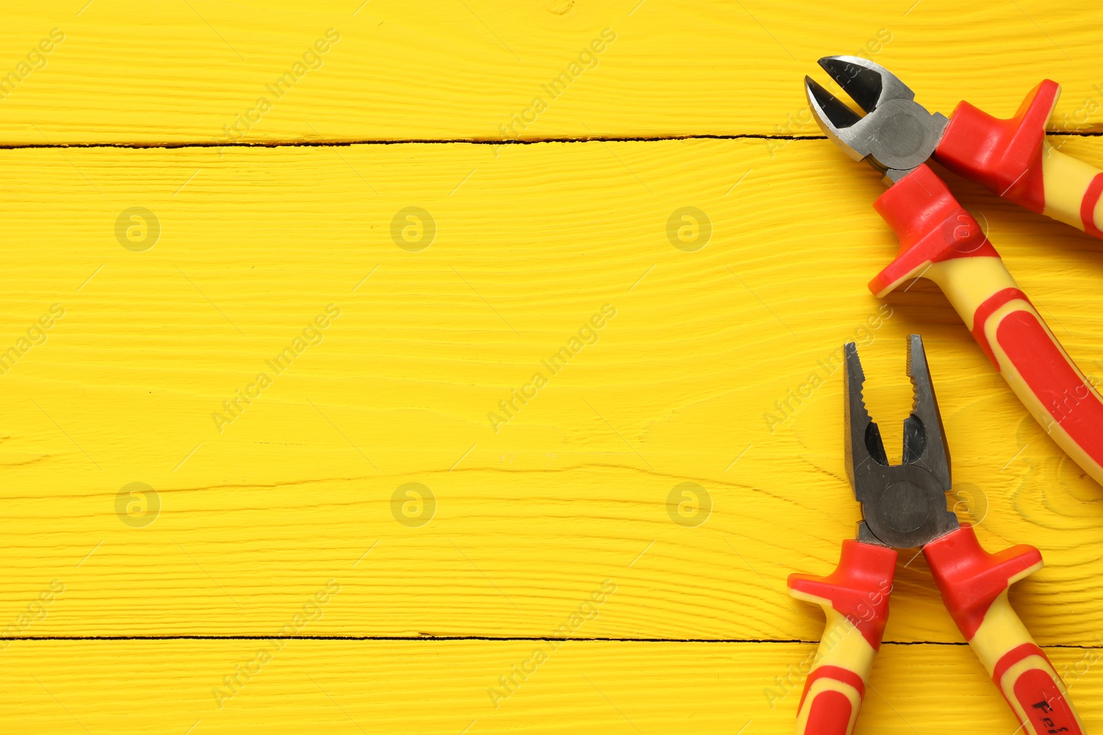 Photo of Pliers on yellow wooden table, flat lay. Space for text