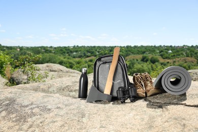 Set of camping equipment on rock outdoors, space for text