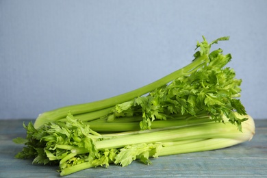 Photo of Fresh ripe celery on blue wooden table. Space for text