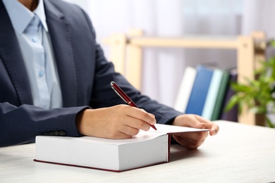 Photo of Writer signing autograph in book at table, closeup