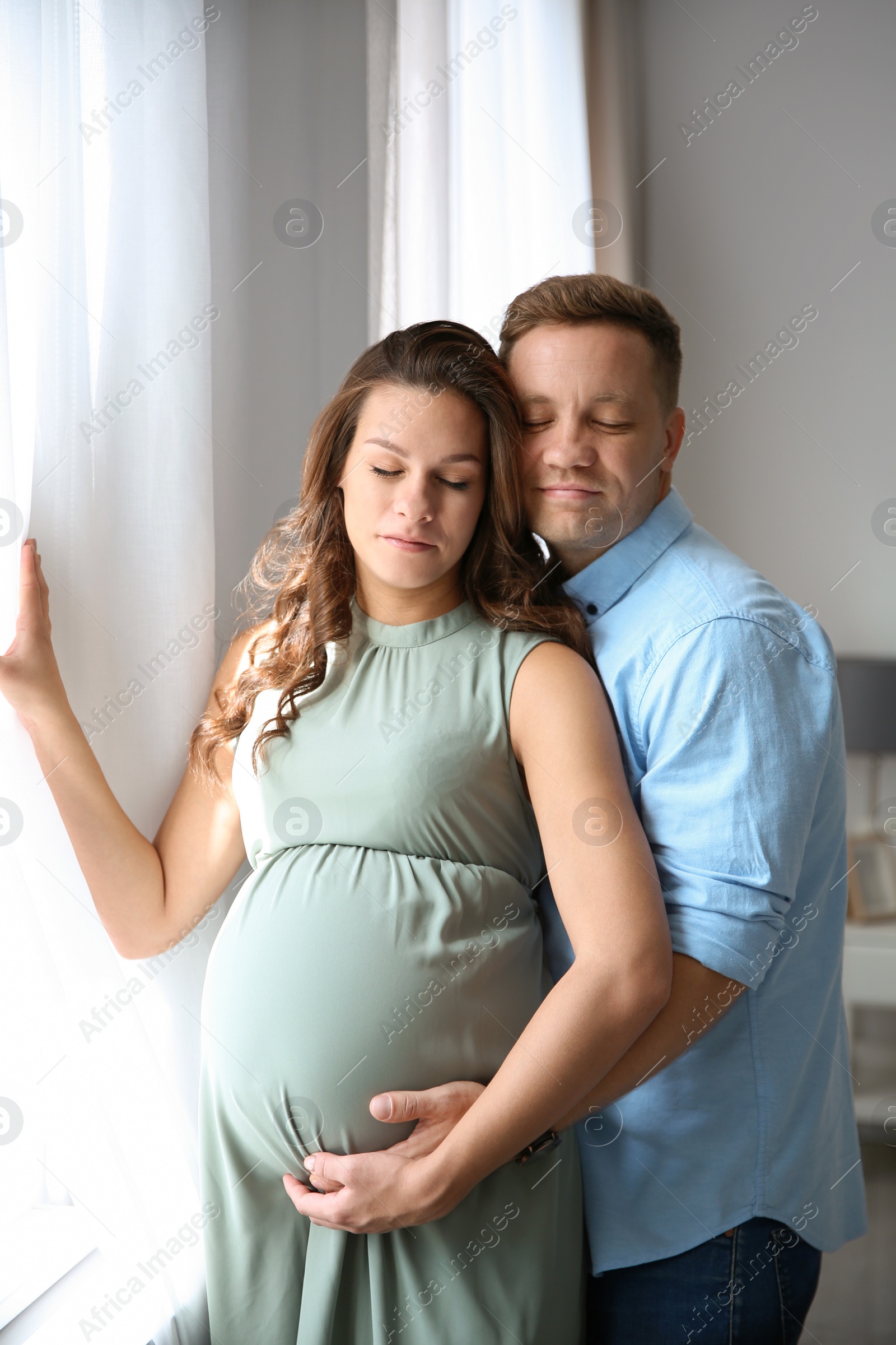 Photo of Pregnant woman with her husband indoors. Happy young family