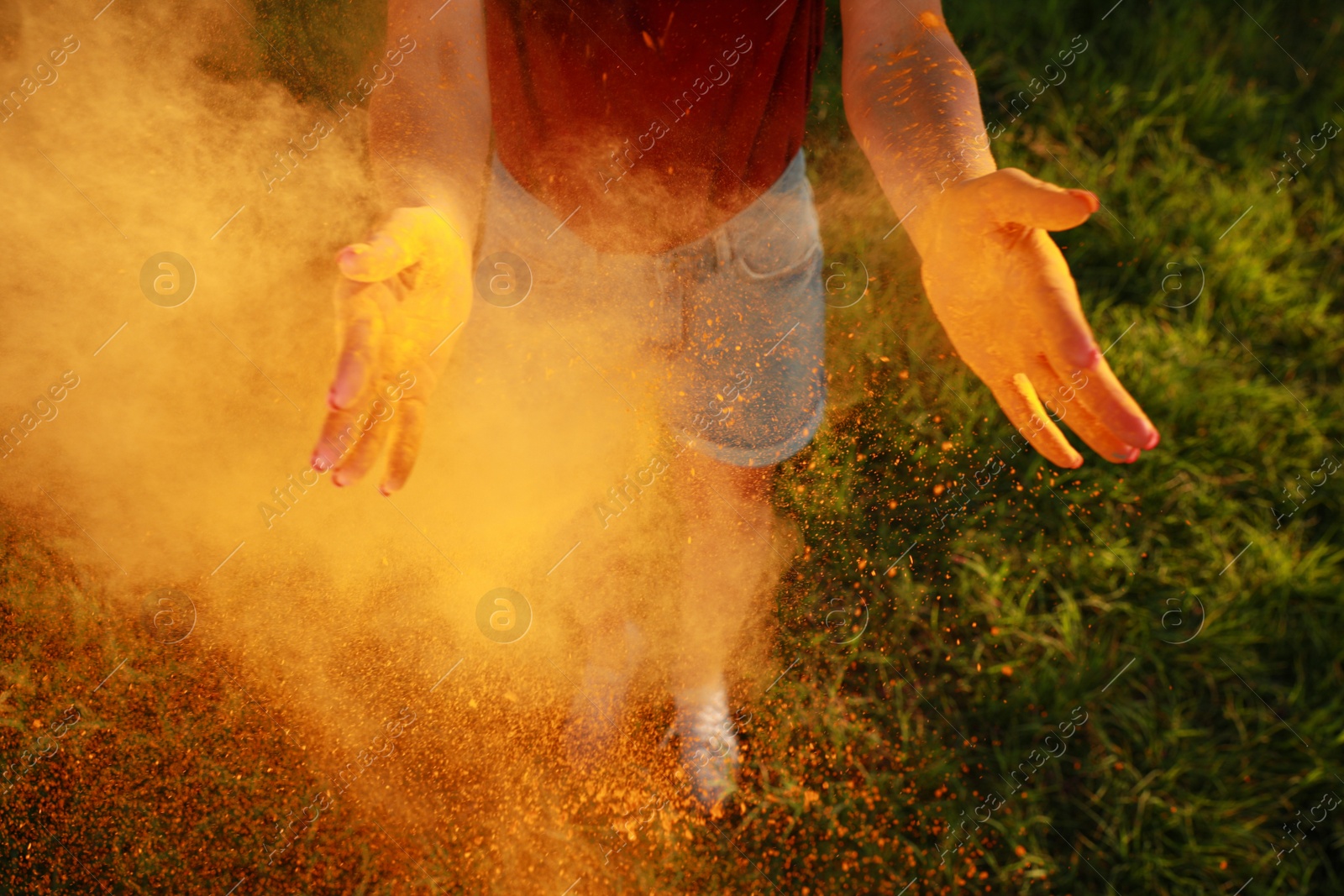 Photo of Woman with orange powder dye outdoors, closeup. Holi festival celebration