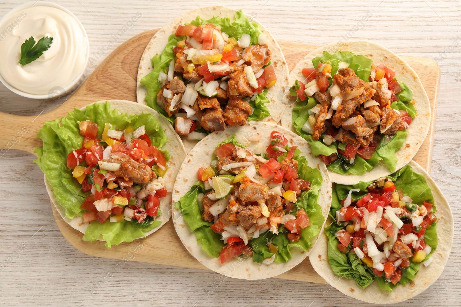 Photo of Delicious tacos with vegetables, meat and sauce on white wooden table, flat lay