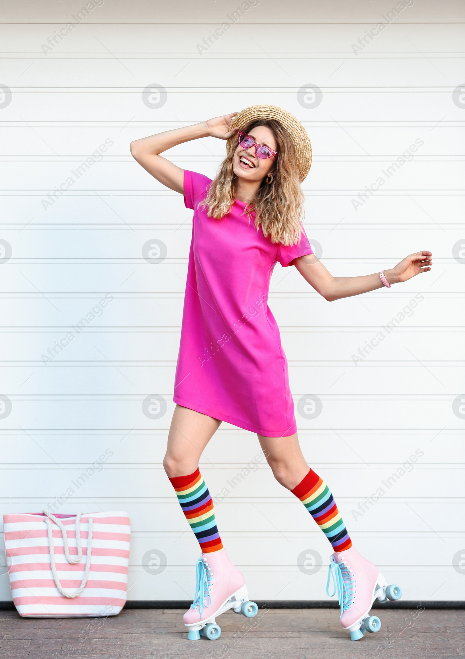 Photo of Happy young woman with retro roller skates near white garage door