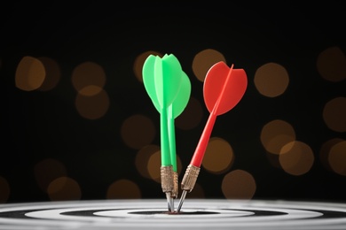 Photo of Arrows hitting target on dart board against blurred lights