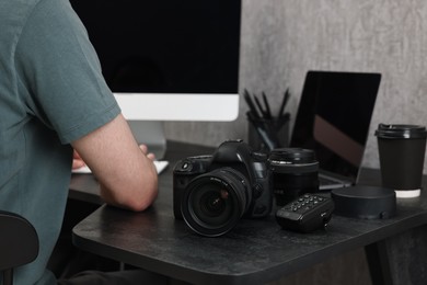 Photo of Photographer working on computer at dark table with camera, closeup