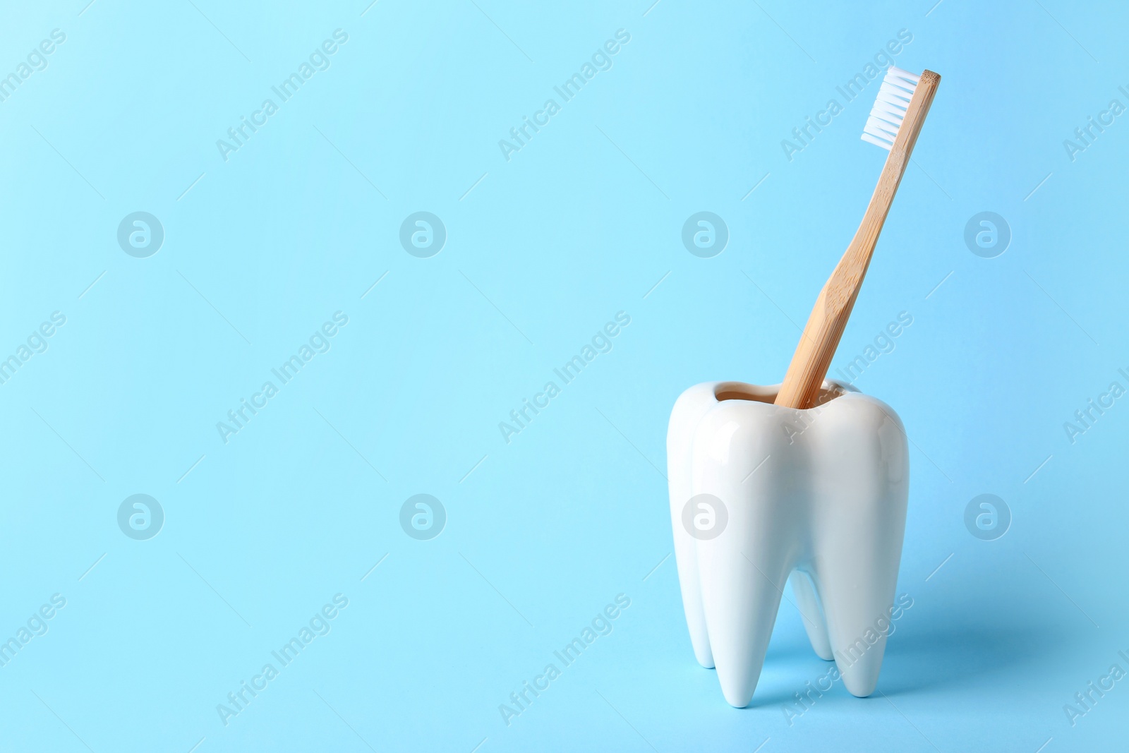Photo of Tooth shaped holder with brush on color background. Space for text