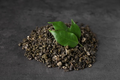 Photo of Heap of dried green tea leaves on grey table