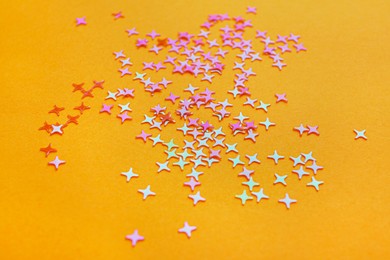 Photo of Shiny bright glitter scattered on orange background