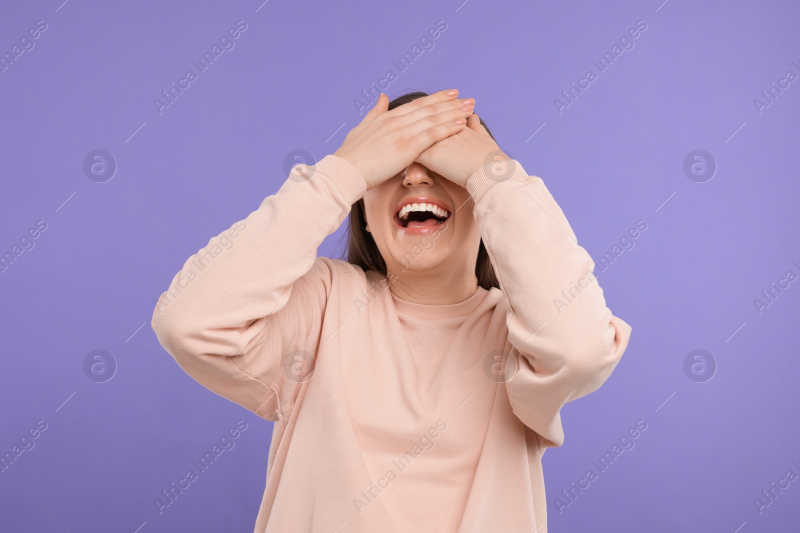 Photo of Woman covering eyes and laughing on violet background