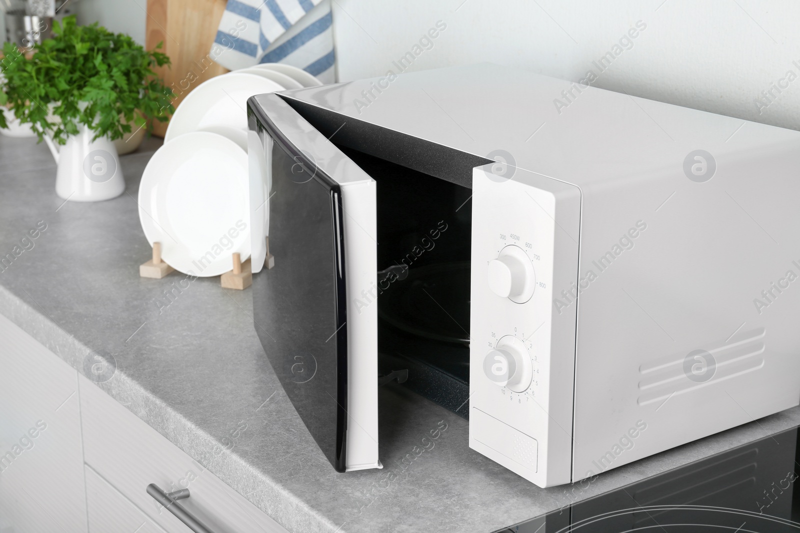 Photo of Open modern microwave oven on table in kitchen