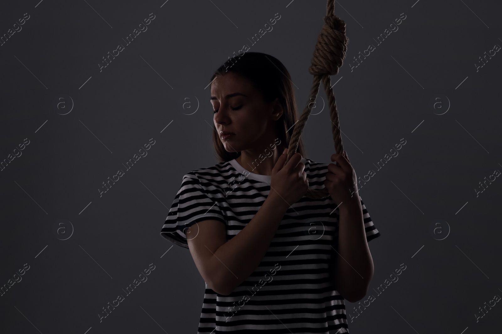 Photo of Depressed woman with rope noose on grey background