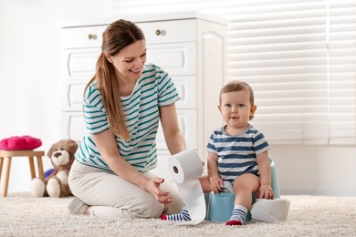 Photo of Mother training her child to sit on baby potty indoors