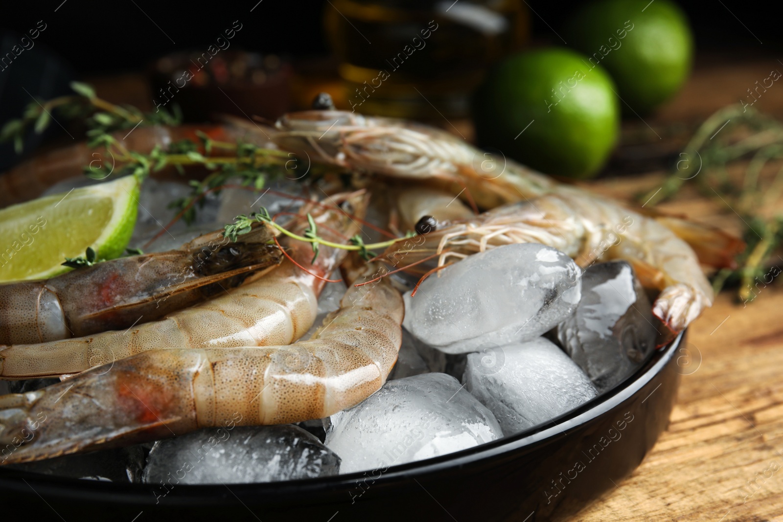 Photo of Fresh raw shrimps with ice on wooden table, closeup