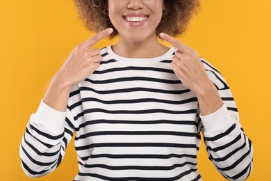 Woman showing her clean teeth on yellow background, closeup