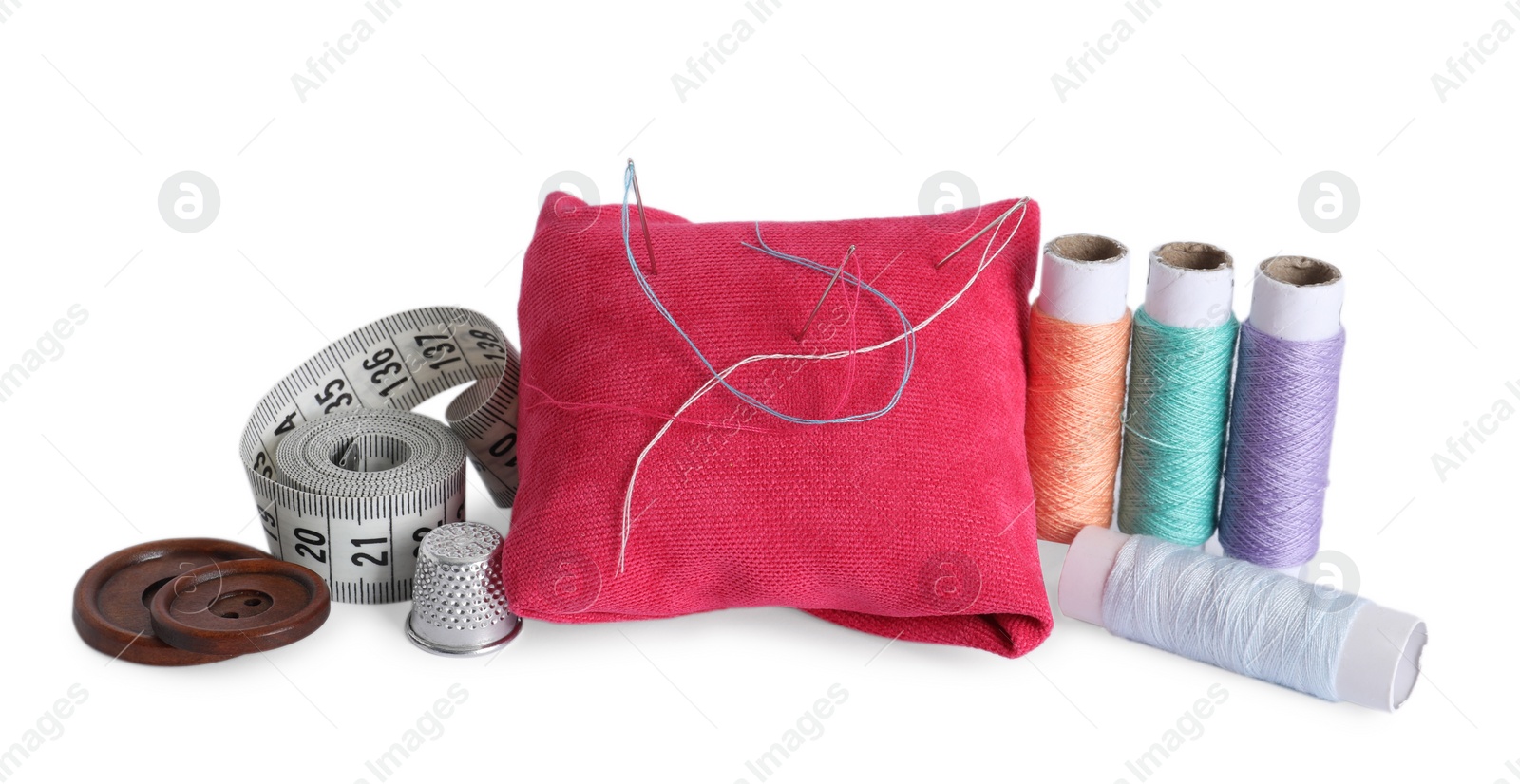 Photo of Pincushion, sewing needles, spools of threads, measuring tape, thimble and buttons isolated on white