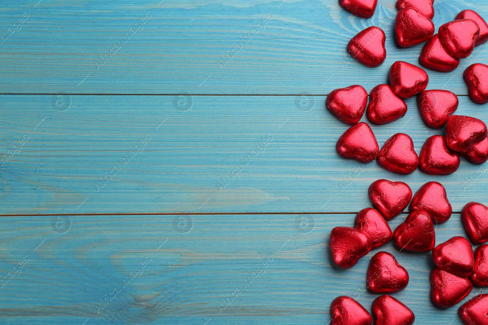 Photo of Heart shaped chocolate candies on blue wooden table, flat lay with space for text. Valentines's day celebration