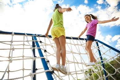Photo of Cute children on playground rope climber outdoors. Summer camp