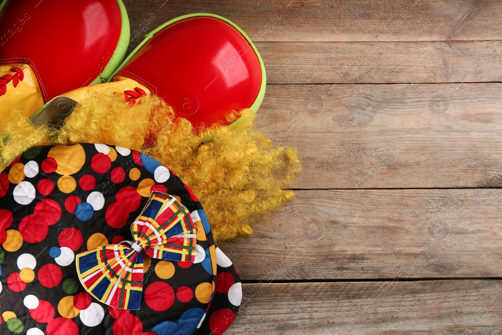 Photo of Flat lay composition with clown's items on wooden table, space for text