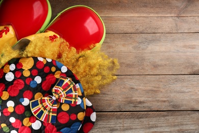 Flat lay composition with clown's items on wooden table, space for text