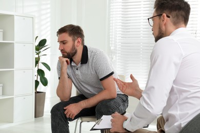 Photo of Psychotherapist working with drug addicted young man indoors