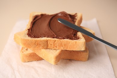 Photo of Tasty toast with chocolate paste and knife on light background