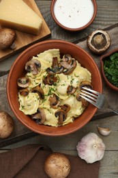 Photo of Delicious ravioli with mushrooms and ingredients on wooden table, flat lay
