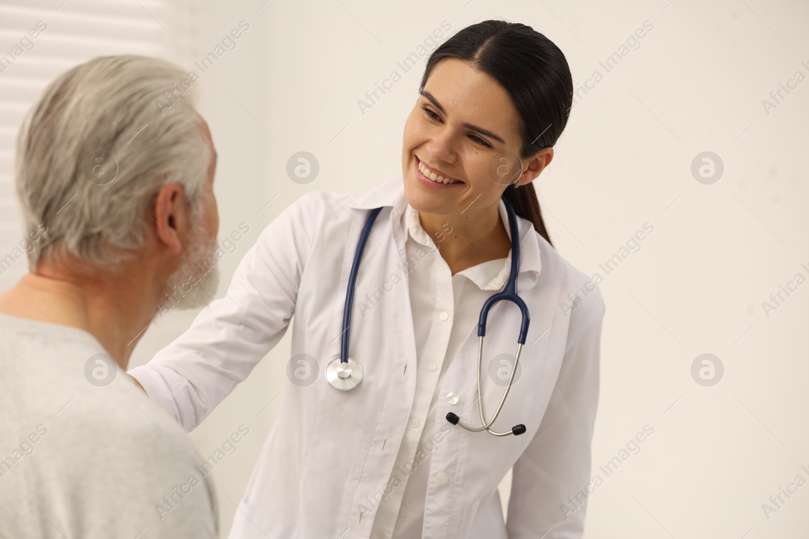 Photo of Smiling nurse supporting elderly patient in hospital