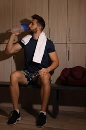 Handsome man drinking water in locker room