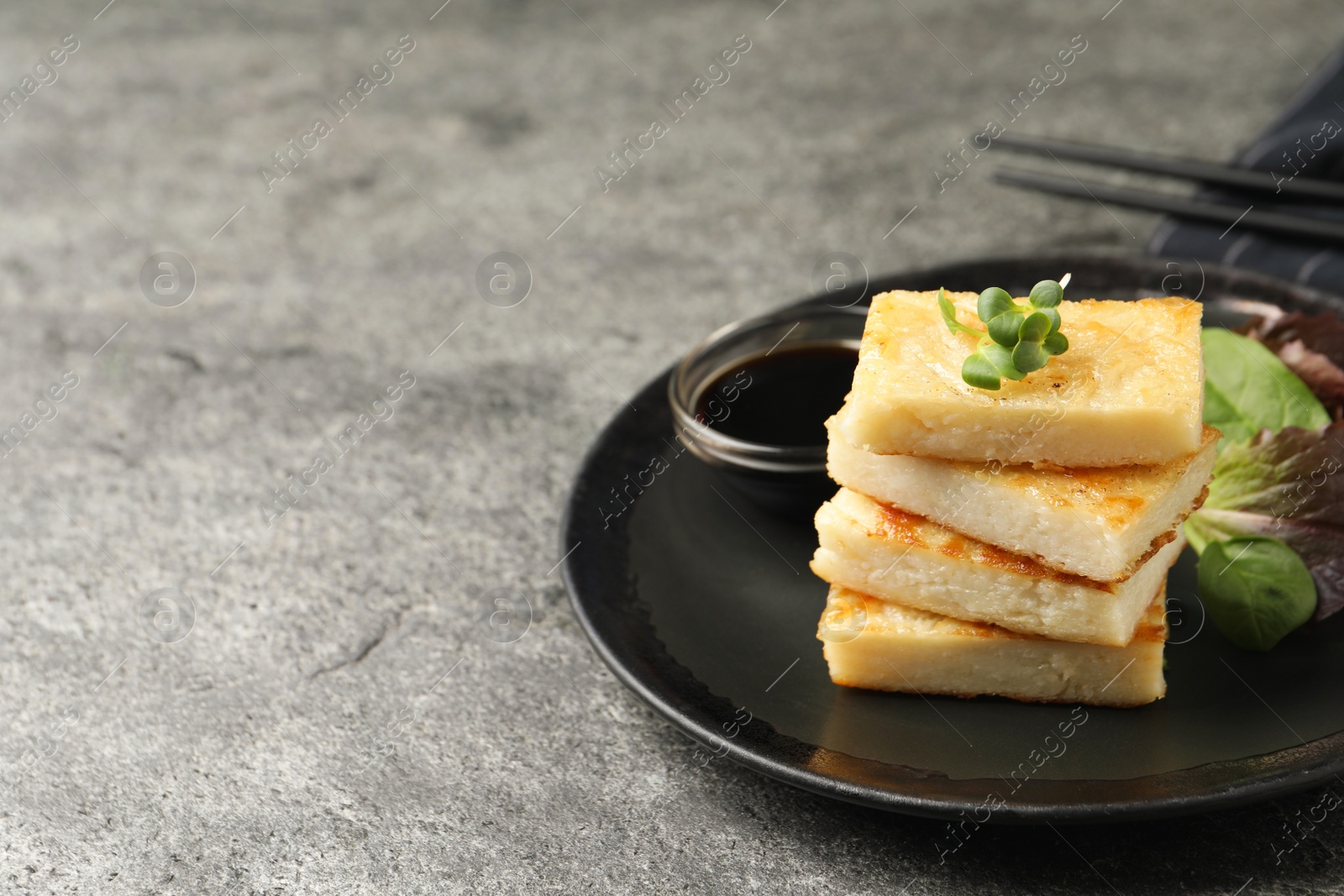 Photo of Delicious turnip cake with herbs served on grey table. Space for text