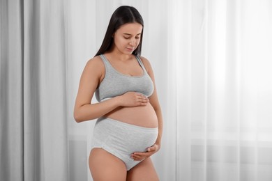 Beautiful pregnant woman in comfortable maternity underwear indoors