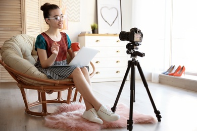 Photo of Young blogger with laptop in lounge chair recording video at home
