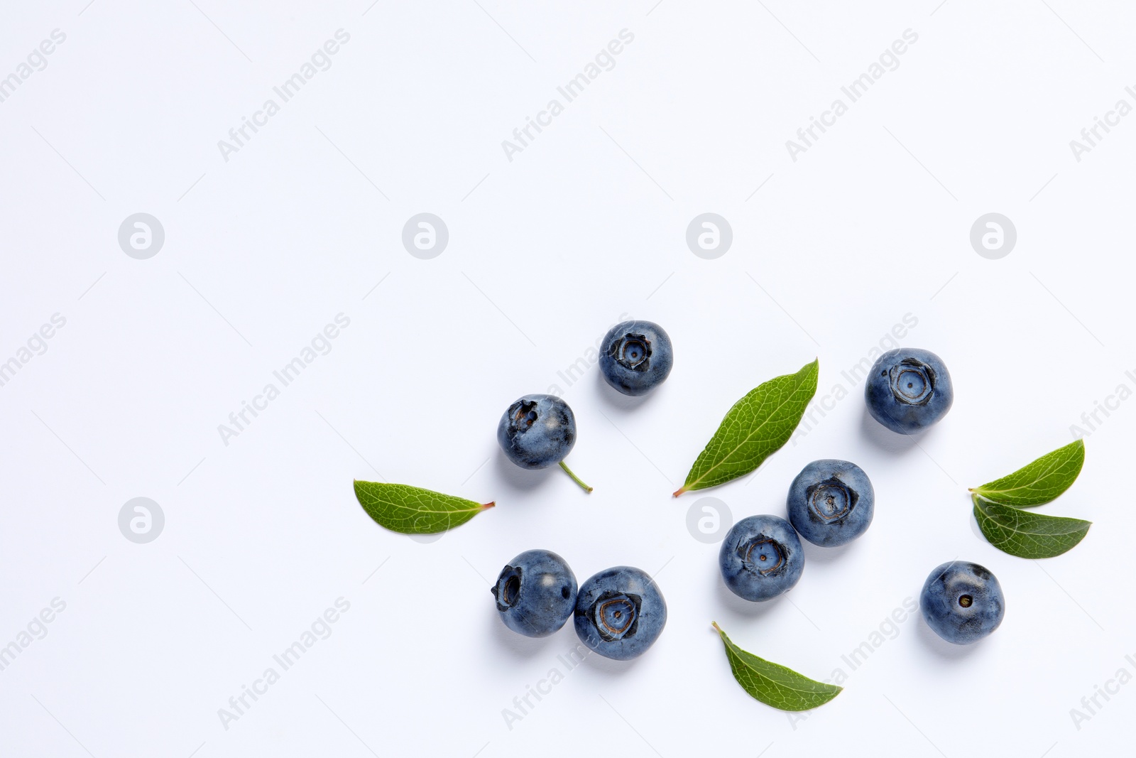 Photo of Tasty fresh blueberries with green leaves on white background, flat lay. Space for text