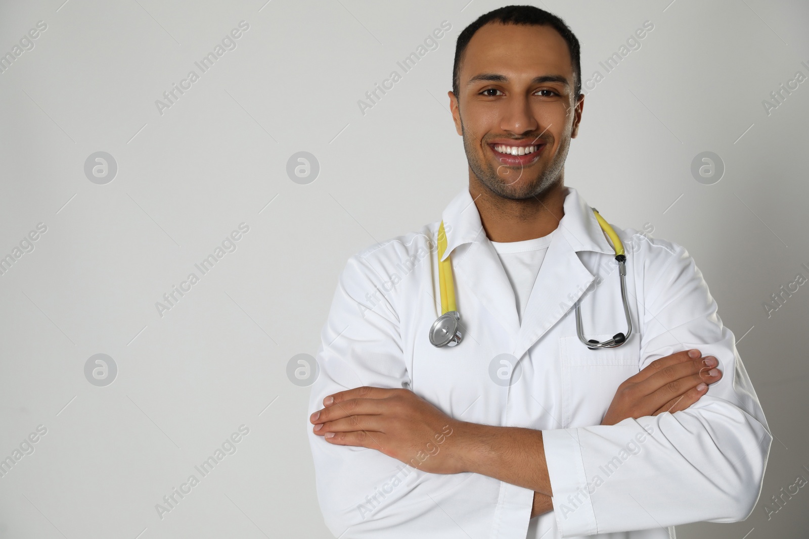Photo of Doctor or medical assistant (male nurse) in uniform with stethoscope on light grey background. Space for text