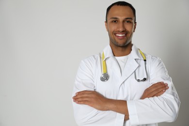 Photo of Doctor or medical assistant (male nurse) in uniform with stethoscope on light grey background. Space for text