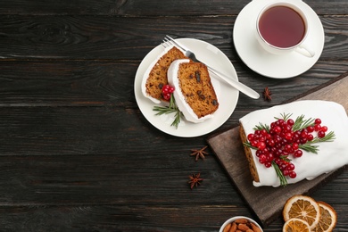 Photo of Traditional Christmas cake and cup of tea on black wooden table, flat lay with space for text. Classic recipe