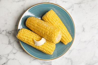 Delicious boiled corn with butter on white marble table, top view