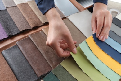 Young woman choosing among upholstery fabric samples, closeup. Interior design