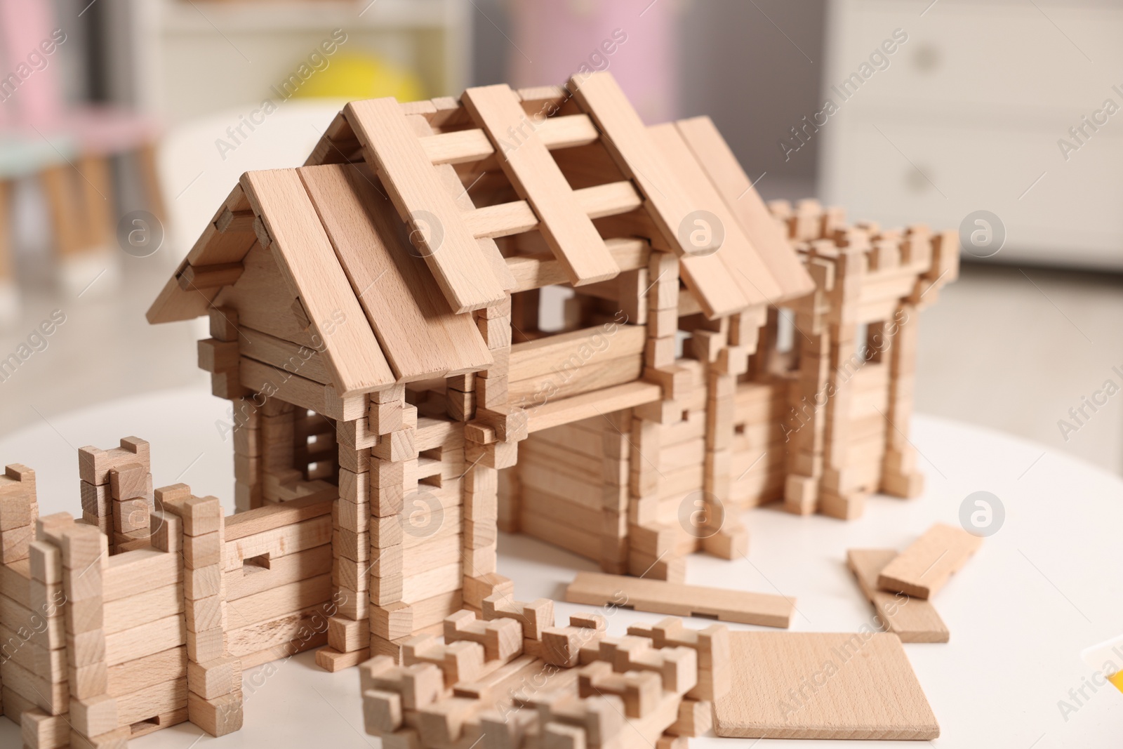 Photo of Wooden entry gate and building blocks on white table indoors. Children's toy