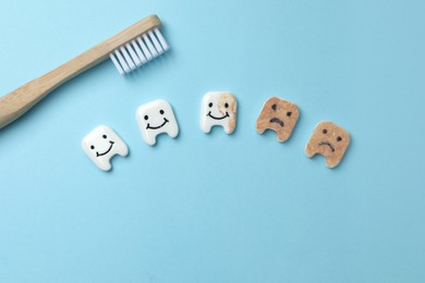 Photo of Clean and dirty decorative teeth near toothbrush on light blue background, flat lay