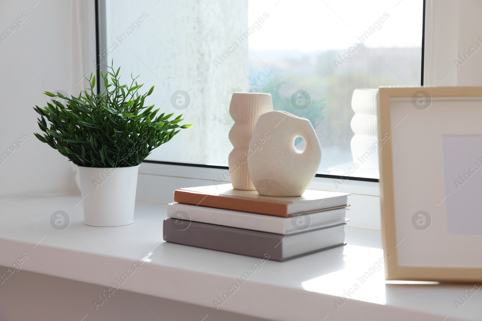 Photo of Potted artificial plant and books on windowsill indoors