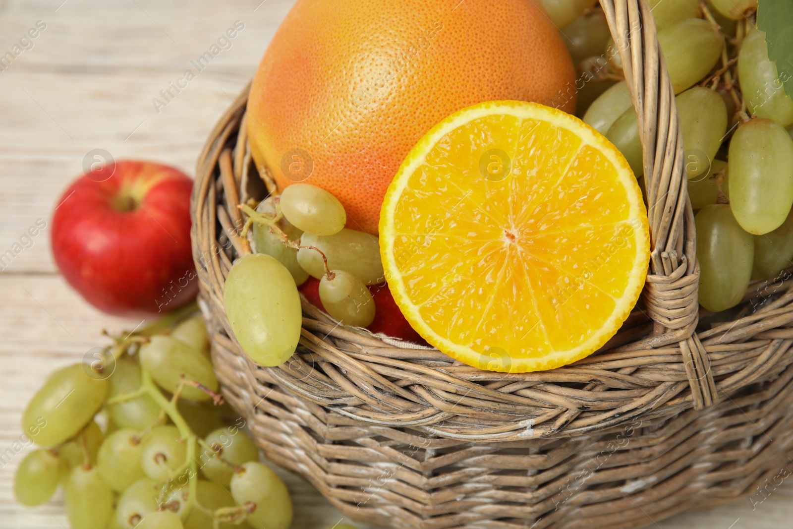 Photo of Different fresh fruits in wicker basket, closeup