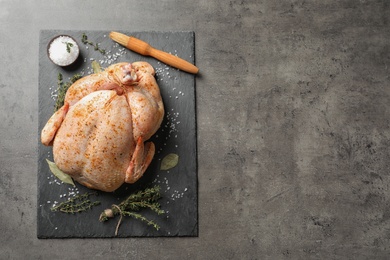 Photo of Slate plate with raw spiced turkey on grey background, top view. Space for text