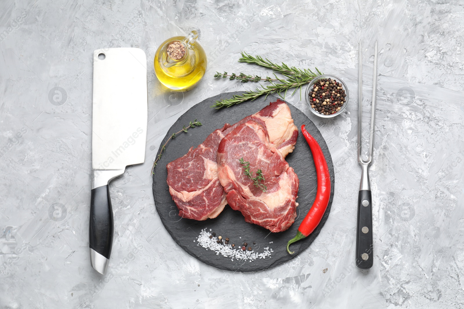 Photo of Fresh raw beef cut, butcher tools and different spices on light grey textured table, flat lay